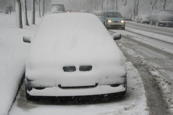 Parked car on street covered in snow