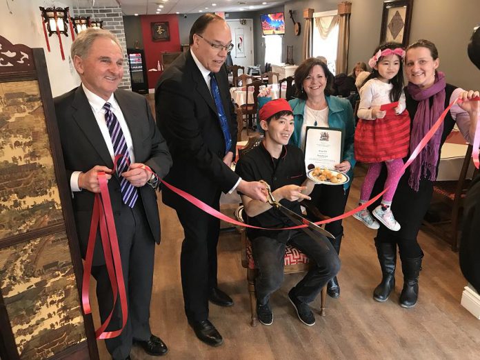 Peterborough Mayor Daryl Bennett cutting the ribbon at the official grand opening of Dragon Yan at 422 Braidwood Avenue in Peterborough on February 16, 2018, whose owner Ron Kam (seated) also made a donation to the New Canadians Centre. Also pictured are city councillors Dan McWilliams and Lesley Parnell, Kam's daughter Heidi, and Hajni Hos, executive director of the New Canadians Centre. (Photo: Daryl Bennett / Twitter)