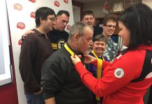 Invictus Games medalist Denise Hepburn (right) hangs her four bronze medals on attendees at a United Way City of Kawartha Lakes announcement that Hepburn will the guest speaker at the orgnaization's Community Champions Touchdown Dinner on March 22, 2018 in Lindsay. (Photo courtesy of United Way City of Kawartha Lakes)