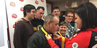 Invictus Games medalist Denise Hepburn (right) hangs her four bronze medals on attendees at a United Way City of Kawartha Lakes announcement that Hepburn will the guest speaker at the orgnaization's Community Champions Touchdown Dinner on March 22, 2018 in Lindsay. (Photo courtesy of United Way City of Kawartha Lakes)