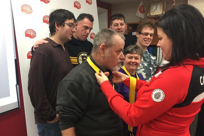 Invictus Games medalist Denise Hepburn (right) hangs her four bronze medals on attendees at a United Way City of Kawartha Lakes announcement that Hepburn will the guest speaker at the orgnaization's Community Champions Touchdown Dinner on March 22, 2018 in Lindsay. (Photo courtesy of United Way City of Kawartha Lakes)