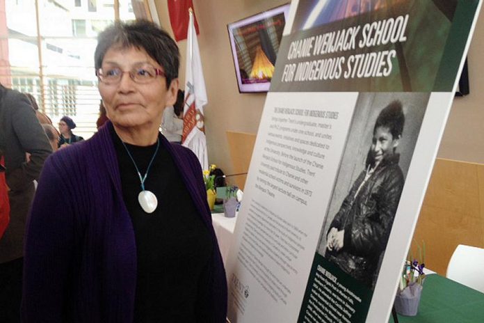 Pearl Achneepineskum, one of Chanie Wenjack's sisters, in front of a photo of her brother. (Photo: Paul Rellinger / kawarthaNOW.com)