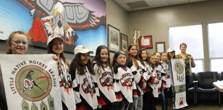 Players from the Curve Lake First Nation Nimkiins Kwe Novice Girls and Atom Girls teams display their championship banners to Chief and Council: Danika Jacobs, Maggie Jevons, Sierra Jacobs, Miley Garbutt, Naomi Coppaway, McKenzie Taylor, Goldie Whetung, Brittany Foster, Abigail Jacobs, Kenzie McIntyre, Marissa Williams, and Chief Phyllis Williams. (Photo courtesy of Curve Lake First Nation)
