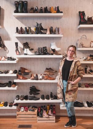 Shelby Leonard-Watt with her wall of shoes, which are both fashion-forward and wildly nostalgic, at the new and expanded S.O.S. location at 384 George Street in downtown Peterborough.  (Photo: Bryan Reid)