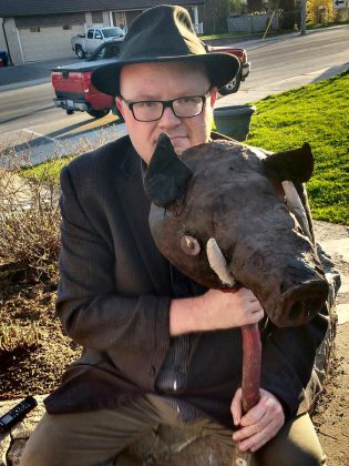 kawarthaNOW's theatre reviewer Sam Tweedle poses with the pig's head, one of the props from the production. 