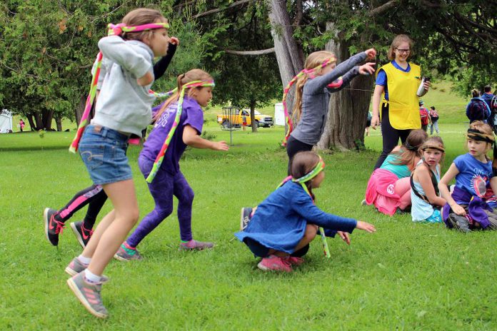 Attendees of this year's Peterborough Children’s Water Festival participate in the Sponge Bog Frog activity centre, led by a high school volunteer, seen in the yellow apron. For this activity, students are frogs who need to hop safely from their hibernation spot to their pond after experiencing both positive and negative events (pollution, garbage, chemicals) along the way. (Photo: Karen Halley / GreenUP)