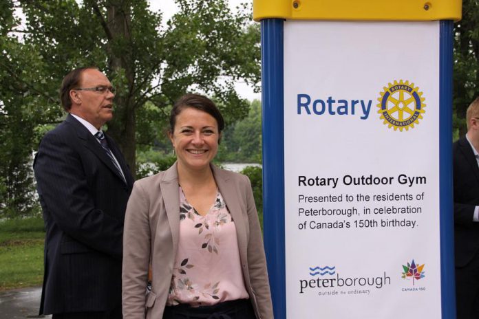 City councillor and mayoral candidate Diane Therrien stands beside the Rotary Outdoor Gym sign. Sevearl years in the making, the project was announced in 2017 as part of Canada's 150th birthday. Peterborough Mayor Daryl Bennett, who also made remarks at the opening, is pictured in the background. (Photo: Jeannine Taylor / kawarthaNOW.com)