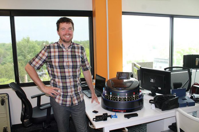 Alex Bushell stands beside the CapTrack, a device he developed with his partner Steve Wright that caps specimen tubes for medical laboratories. (Photo: Amy Bowen / kawarthaNOW.com)