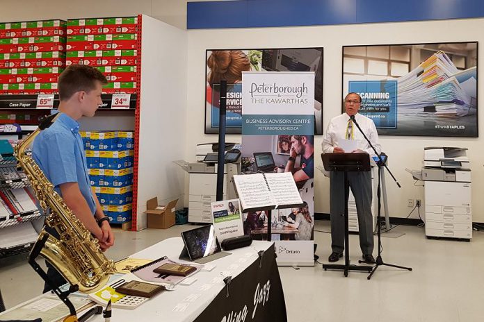 Peterborough Mayor Daryl Bennett speaks at the Summer Company-Staples Youth Entrepreneurship Day on July 4, 2018 at Staples in Peterborough, as young entrepreneur Noah Abrahamse of GoldWing Jazz looks on. (Photo: Amy Bowen / kawarthaNOW.com)