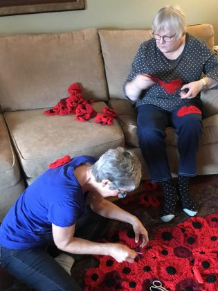 Hospice volunteers Joyce Close and Elizabeth Jewell work on stitching all the poppies together for the 2018 installation.  (Photo: Barb Shaw)