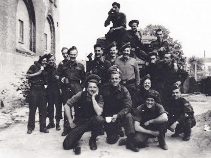 Radio operator Joseph Sullivan (rear row, right) with his signals platoon in Emden, Germany, on Victory in Europe (VE) Day on May 8, 1945. A signals platoon in an infantry battalion was responsible for maintaining communication between the companies of the battalion and battalion headquarters.   (Photo courtesy of Joseph Sullivan)