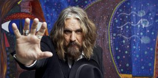 Veteran Canadian musician Tom Wilson, pictured in front of some of his paintings, accidentally discovered seven years ago both that he was adopted and his birth parents were Indigenous, leading him to write his critically acclaimed autobiography "Beautiful Scars" in 2017. Wilson, who performs as Lee Harvey Osmond, is releasing his latest album "Mohawk" on January 25, 2019. He will be performing songs from the new record and more at his February 2nd concert at the Market Hall Performing Arts Centre in downtown Peterborough, sponsored by kawarthaNOW. (Photo: Marta Hewson)