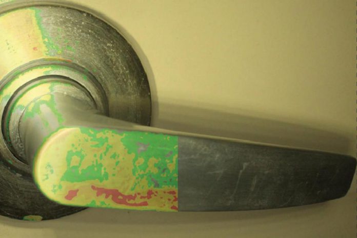 The left side of photo shows actual microbial contamination detected on a door handle by  Charlotte Products Ltd.'s OptiSolve Pathfinder environmental monitoring system and optical sensor technology, with the right side of the photo showing how the door handle looks to the naked eye. (Photo:  Charlotte Products Ltd.)