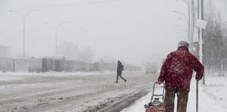Older woman walking in a winter snow storm