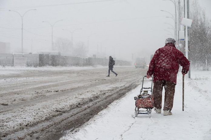 Older woman walking in a winter snow storm