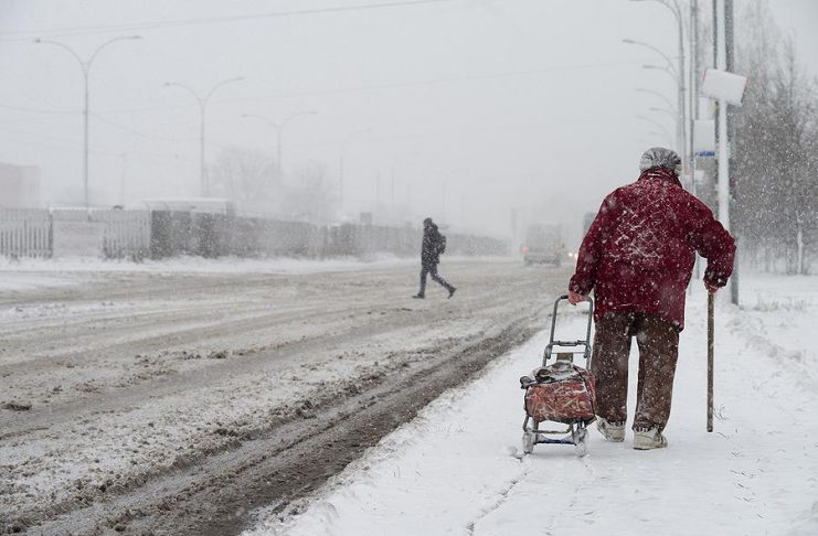Older woman walking in a winter snow storm