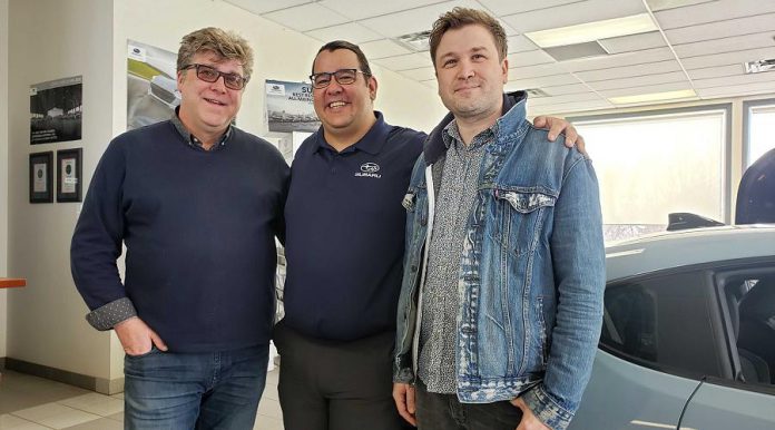 Peterborough Folk Festival board chair Malcolm Byard (left) and vice chair and artistic director Ryan Kemp (right) with Phillip Jolicoeur, sales and marketing specialist at Peterborough Subaru, during the announcement on  March 19, 2019 at the car dealership's showroom on Chemong Road that Peterborough Subaru is sponsoring the 2019 summer festival. (Photo: Jeannine Taylor / kawarthaNOW.com)