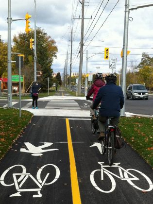 People ride bikes and walk along the multi-use trail on Ashburnham Drive, Peterborough. Log your walking, biking, transit, and carpooling trips this May to win prizes.  (Photo courtesy of GreenUP)