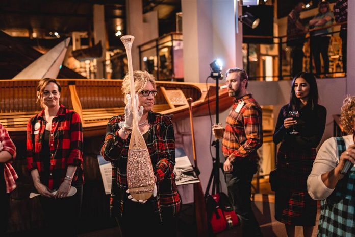 Jane Ulrich, head of the volunteer organizing committee, displays one of the 15 paddles that were auctioned off at the inaugural Campfires & Cocktails fundraiser at The Canadian Canoe Museum on May 4, 2019. (Photo: Bryan Reid)