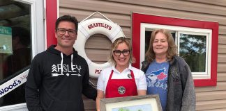 Yannick Bisson, who portrays William Murdoch on CBC television's award-winning series "Murdoch Mysteries", and his wife Shantelle Bisson at Shantilly's Place (formerly West Bay Narrows Marina) on Chandos Lake in North Kawartha. Also pictured is artist Terri Butler (right), who gifted the couple a painting of the original West Bay Narrows Marina. The Bissons, who have a cottage on the lake, purchased the marina in 2018. Shantilly's Place opened for the summer season on May 17, 2019. (Photo: Shantilly's Place)