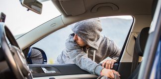 Thief stealing bag through open window of car