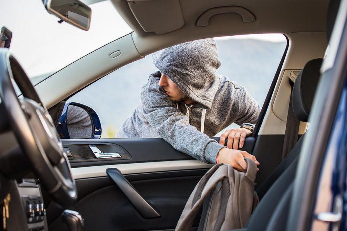 Thief stealing bag through open window of car