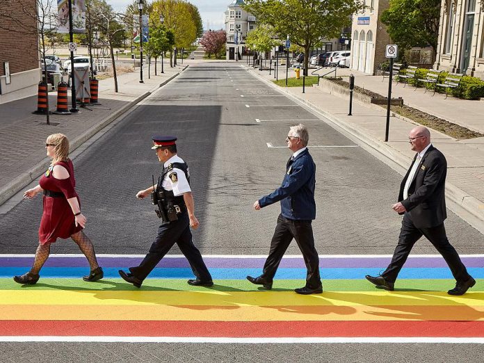 Representatives from community groups, the Cobourg Police Service, and the Town of Cobourg mimic the famous cover of The Beatles' Abbey Road album during the celebration of the new rainbow crosswalk at King Street West and Second Streets in downtown Cobourg. The crosswalk, which was unveiled during Pride Month in Cobourg, will remain in place for the rest of the summer. (Photo: Town of Cobourg / Facebook)