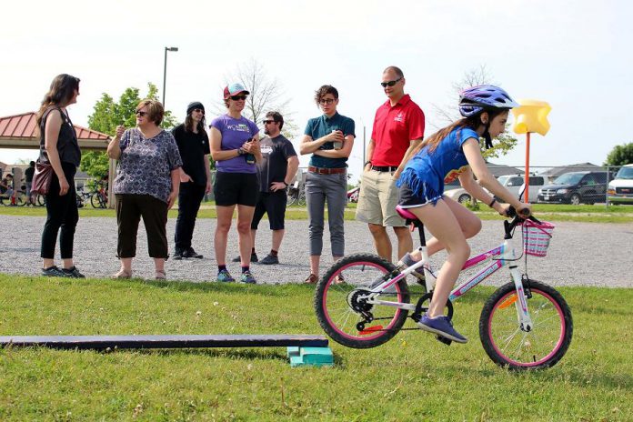 A Grade 5 student from Monsignor O'Donahue Catholic Elementary School demonstrates her riding skills on the Bike Playground, while funders and partners of the Pedal Power program look on. (Photo: Karen Halley)