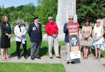 Port Hope Rotary Club president Bob Wallace presents a mock-up of the Avenue of Heroes banners at the Memorial Park cenotaph on June 19, 2019. The banners will be installed along streets in downtown Port Hope this fall. Pictured on the mock-up is a photo of George Narraway, a World War II veteran and the late father of Kevin Narraway, a manager in Port Hope's marketing and tourism department, which is leading the banner design. (Photo: April Potter / kawarthaNOW.com)