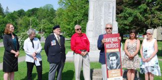 Port Hope Rotary Club president Bob Wallace presents a mock-up of the Avenue of Heroes banners at the Memorial Park cenotaph on June 19, 2019. The banners will be installed along streets in downtown Port Hope this fall. Pictured on the mock-up is a photo of George Narraway, a World War II veteran and the late father of Kevin Narraway, a manager in Port Hope's marketing and tourism department, which is leading the banner design. (Photo: April Potter / kawarthaNOW.com)