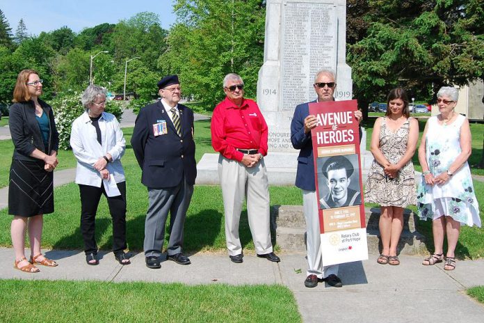 Port Hope Rotary Club president Bob Wallace presents a mock-up of the Avenue of Heroes banners at the Memorial Park cenotaph on June 19, 2019. The banners will be installed along streets in downtown Port Hope this fall. Pictured on the mock-up is a photo of George Narraway, a World War II veteran and the late father of Kevin Narraway, a manager in Port Hope's marketing and tourism department, which is leading the banner design. (Photo: April Potter / kawarthaNOW.com)