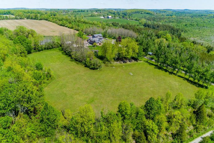 An aerial view of 124 Lily Lake Road, which sits on 100 acres or forest and fields, providing unparalleled privacy.