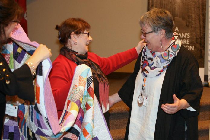 As well as leadiAs well as leading The T-R Group's coaching and learning practice area and running independent psychotherapy practice Growing Edge, Colleen Carruthers is a an avid quilter.  Here Colleen presents a quilt to Louise Racine (right), founder of the International Women's Day Peterborough conference. (Photo: IWD PTBO conference)ng The T-R Group's coaching and learning practice area and running independent psychotherapy practice Growing Edge, Colleen Carruthers is a an avid quilter. In 2017, she coordinated the 150 Canadian Women Quilt project for the Women’s Business Network of Peterborough (WBN). The quilt, which honoured unsung female heroes of Canada's history, was raffled off at WBN's June 2017 gala with proceeds going to YWCA Crossroads Shelter. Here Colleen presents the quilt to Louise Racine (right), founder of the International Women's Day Peterborough conference. (Photo: WBN)