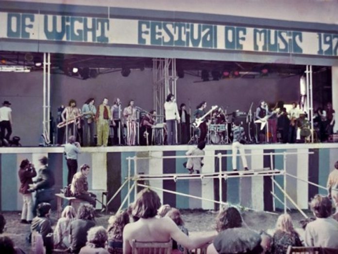 Lighthouse turned down an invitation to perform at Woodstock in 1969, but the following year they played the even bigger Isle of Wight Festival in England, sharing the stage with the likes of Jimi Hendrix, The Doors, The Who, The Moody Blues, Joni Mitchell, and many more. From left: Keith Jollimore, Howard Shore, Pete Pantaluk, Bruce Cassidy, Larry Smith, Paul Hoffert, Bob McBride, manager Vinnie Fusco standing at back, Louis Yachnin, Skip Prokop, Ralph Cole, Don DiNovo, Paul Armin, and Dick Armin. (Photo courtesy of Hoffert Communications)