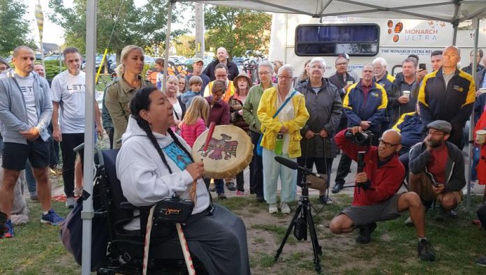 Dorothy Taylor from Curve Lake, who performed an opening blessing as well as a smudging for the runners and provided protective herbs for the  Monarch Ultra runners, with the run's co-founder Carlotta James behind her and co-founder and filmmaker Rodney Fuentes at right documenting.  (Photo: Jeannine Taylor / kawarthaNOW.com)