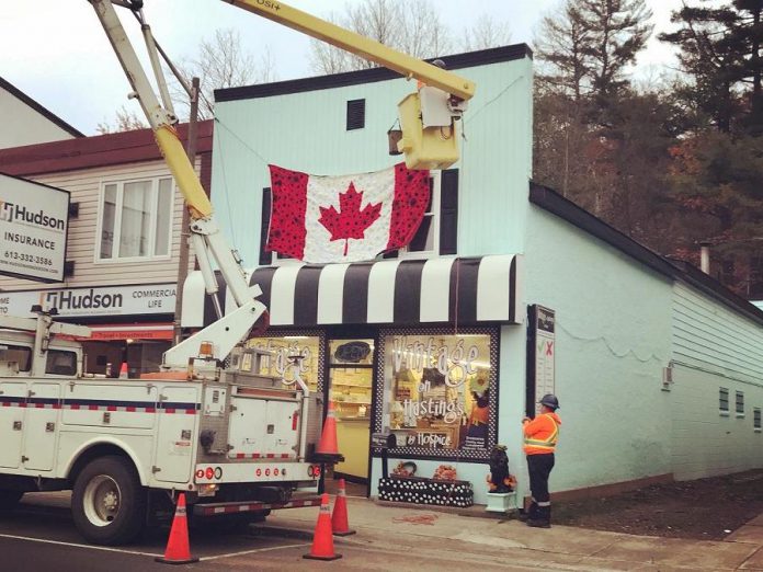 Staff from the Town of Bancroft assisted with the installation of the hand-crafted poppy flag on the outside of the second floor of Vintage on Hastings in Bancroft. (Photo: Barb Shaw)