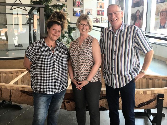 Local Anishinaabe artist Tia Cavanagh (left) with Kim and Mark Zippel in front of a canoe made by Anishinaabe master birchbark canoe builder Chuck Commanda from the community of Kitigan Zibi in Quebec. The canoe is currently on display at the entrance to Peterborough & the Kawarthas Tourism Visitor Centre, immediately opposite the Jiimaan'ndewemgadnong pocket park site outside of Euphoria Wellness Spa in downtown Peterborough. Kim and Mark Zippel sponsored the two canoe-themed public art pieces that Cavanagh is currently working on for the Jiimaan'ndewemgadnong site. (Photo courtesy of GreenUP)