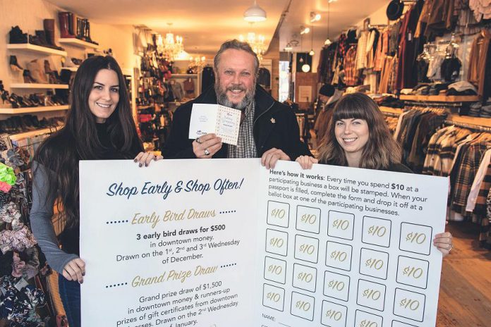 Terry Guiel, executive director of the Peterborough Downtown Business Improvement Area (DBIA), and Wendy Gillis and Malissa Almond hold up a giant Holiday Shopping Passport as they celebrate the launch of the annual downtown shopping program on November 12, 2019 at Save Our Soles (385 George St. N., Peterborough), one of the 148 businesses and organizations in downtown Peterborough participating in the program. Shoppers get a stamp every time they spend $10 at one of the participating locations, and completed passports are entered into a draw for "downtown money" that can be redeemed at participating locations. (Photo courtesy of Peterborough DBIA)