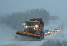 Snow plow on highway during snow squall