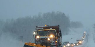 Snow plow on highway during snow squall