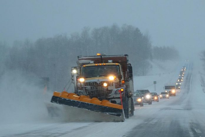 Snow plow on highway during snow squall