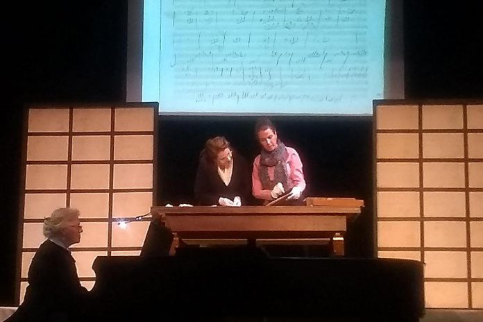 In a scene from the Peterborough Theatre Guild's production of "33 Variations", Dr. Gertrude Landenburger (Gayle Fraser, right) explains Beethoven's compositional techniques to Dr. Katherine Brandt (Jane Werger, middle) as an image of Beethoven's actual work is projected on a screen behind them. Pianist Karen Locklin (left) performs Beethoven's Diabelli Variations throughout the play, making the music a character in its own right. (Photo: Sam Tweedle)