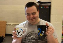 Josh, a member of The Biz Group, displays two of the group's hand-painted mugs created for Y Drive and Peterborough Challenger Baseball. The group is also selling "love mugs" and plans to expand with hand-painted tote bags and t-shirts. All proceeds from the sales of items go directly to members of The Biz Group, an initiative supported by the Down Syndrome Association of Peterborough. (Photo courtesy of Down Syndrome Association of Peterborough)