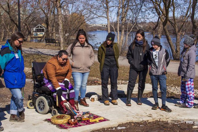 At the Depave site at 100 Water Street in downtown Peterborough, Anishinaabe elder Dorothy Taylor of the Curve Lake First Nation explains the significance of the materials she uses to perform water ceremony to students from St. Anne's Catholic Elementary School. In partnership with GreenUP's Wonders of Water program, the students are transforming a flood-prone corner of their school yard into a rain garden. They also took a tour of the local watershed, tracing Jackson Creek from its headwaters at Loggerhead Marsh to its outflow at the Otonabee River, near the Depave site. (Photo: GreenUP)