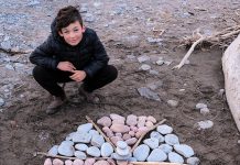 Port Hope artist Lee Higginson's son Sam with his creation at West Beach in Port Hope. Lee and her sons Sam and Charley, who are both young artists, hope to make as much public art as they can during the COVID-19 shutdown. (Photo courtesy of Lee Higginson)