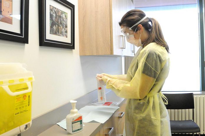 Public health nurse Simone Jackson wearing personal protective equipment as she prepares to open a swab to test a patient for COVID-19 in Peterborough Public Health's clinic. (Photo courtesy of Peterborough Public Health)