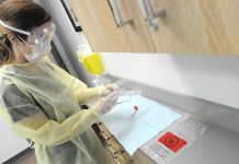 Public health nurse Simone Jackson wearing personal protective equipment as she prepares to open a swab to test a patient for COVID-19 in Peterborough Public Health's clinic. (Photo courtesy of Peterborough Public Health)