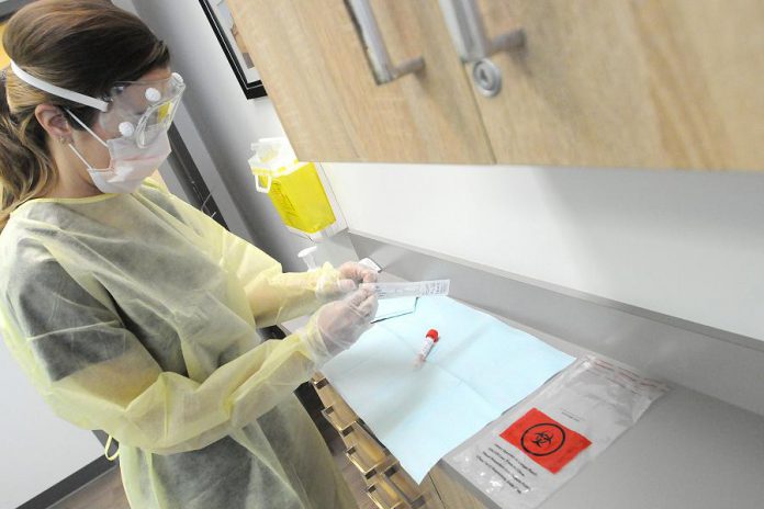 Public health nurse Simone Jackson wearing personal protective equipment as she prepares to open a swab to test a patient for COVID-19 in Peterborough Public Health's clinic. (Photo courtesy of Peterborough Public Health)