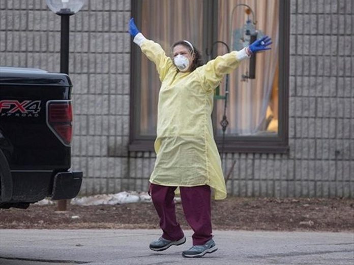 A health care worker at Pinecrest Nursing Home in Bobcaygeon, Ontario  responds to passing cars honking support on Tuesday, March 31, 2020. (Photo: Fred Thornhill / The Canadian Press)