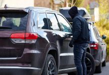 A thief trying the door of a parked vehicle